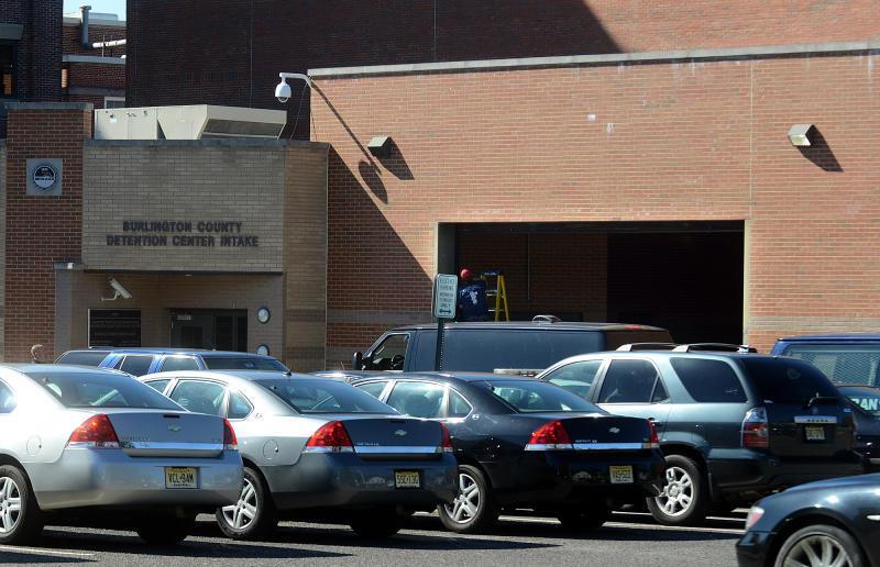 A row of cars parked in front of the Burlington County Detention Center Intake brick building on a sunny day