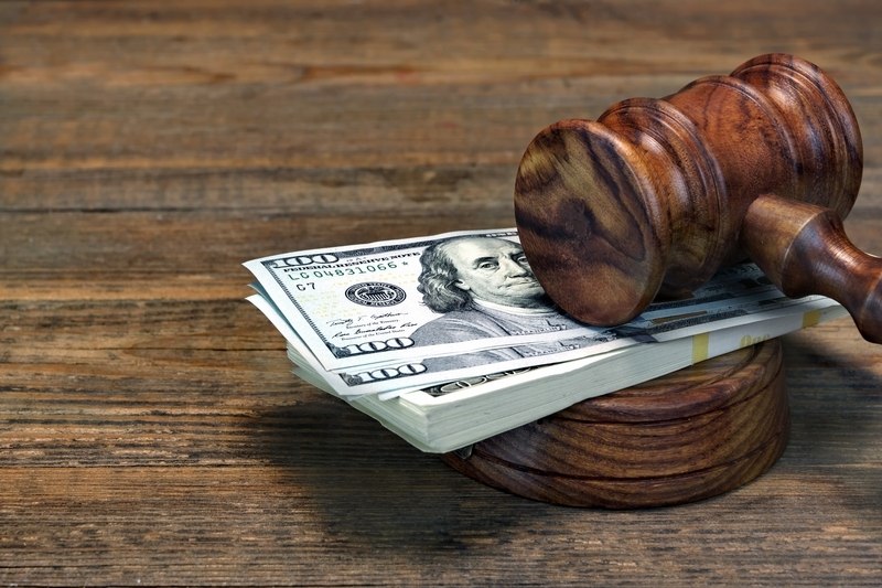 Judge’s gavel resting on a stack of hundred-dollar bills