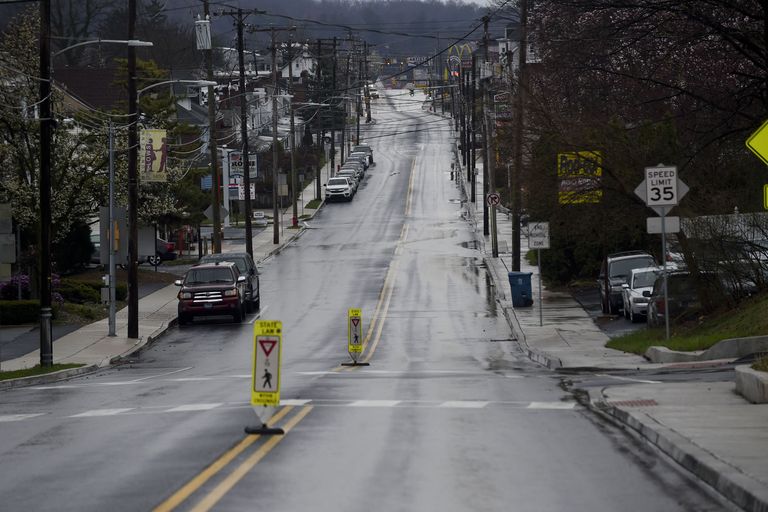 A wet suburban road with a 35 MPH speed limit sign and crosswalk markers