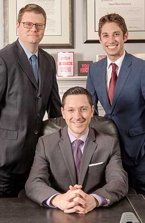 Group portrait of Rosenberg | Perry & Associates attorneys. Front: Daniel M. Rosenberg; Back left: Robert M. Perry; Back right: Nathan J. Mammarella