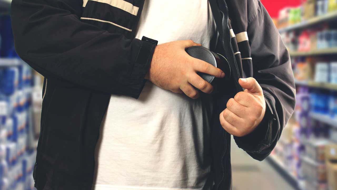 A man hiding a pair of headphones in his jacket.